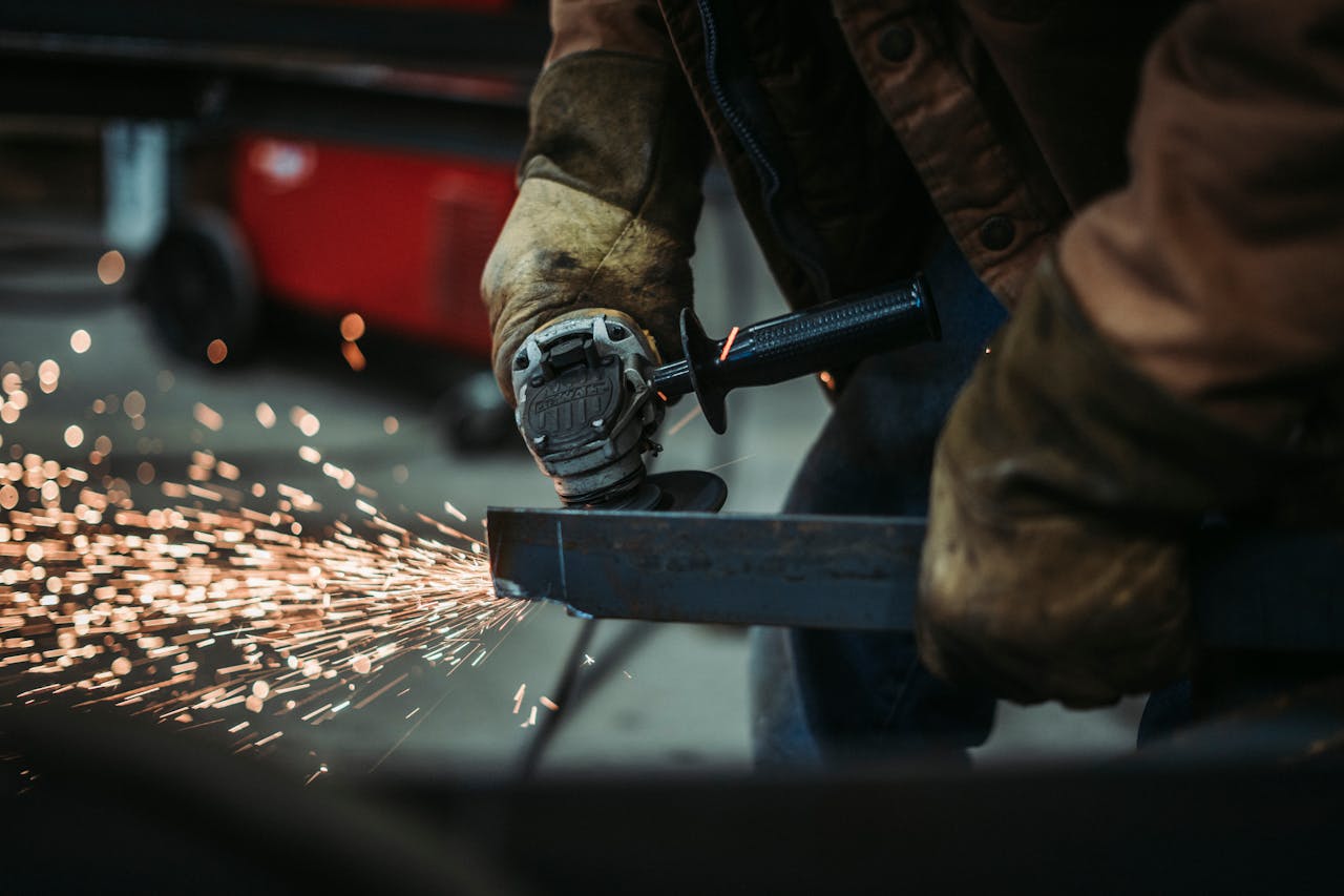 A skilled worker using an angle grinder sparks fly as they cut metal in a workshop.