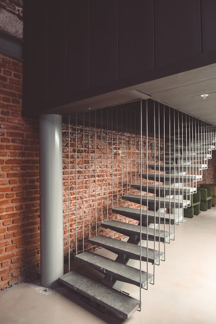 Contemporary suspended staircase with metal profiles against a brick wall in Istanbul.