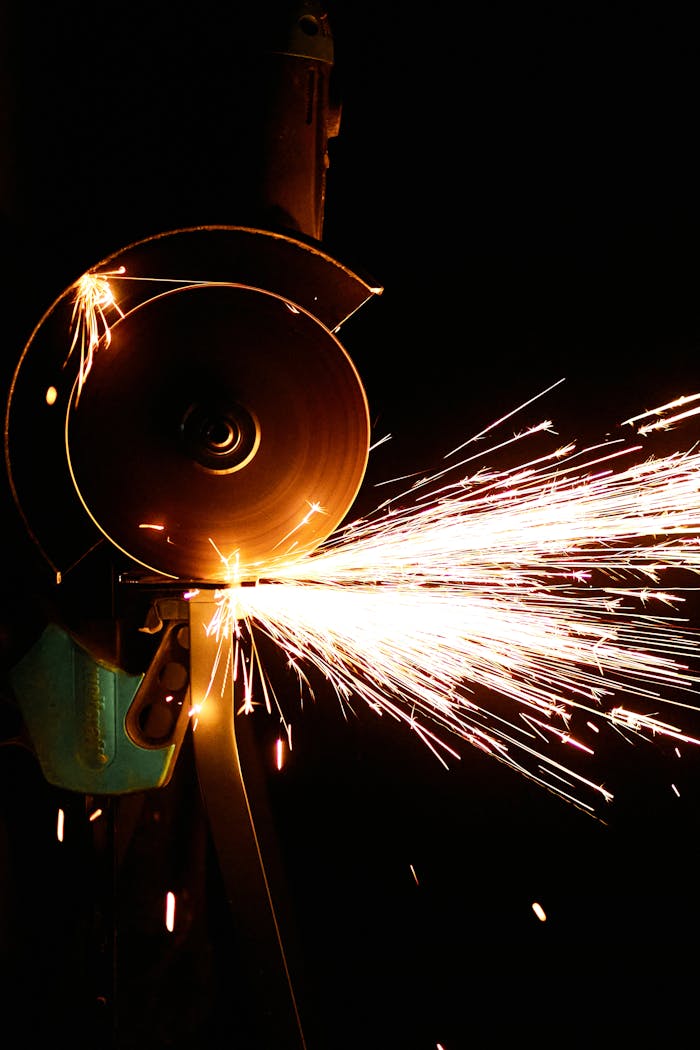 Close-up of an angle grinder in action, producing vibrant sparks against a dark background.